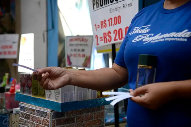 Tomaz Silva/Agência Brasil Vendedora entrega fragrâncias aos pedestres em loja na tradicional área de compras do Saara, no centro do Rio de Janeiro
